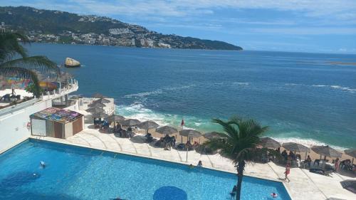ein Swimmingpool mit Blick auf das Meer in der Unterkunft Hermosa Suite a Pie de Playa en Acapulco in Acapulco