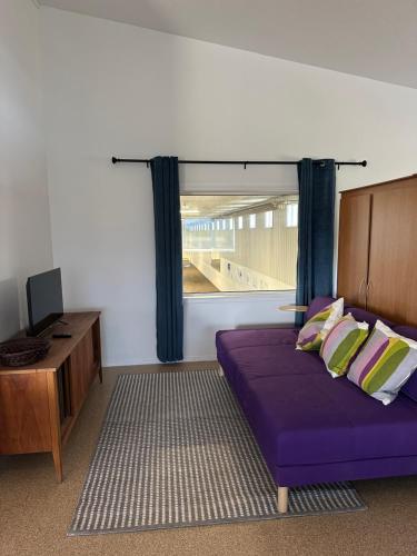 a bedroom with a purple bed and a window at Mezzanine Loft Above the Barn in Whitehorse
