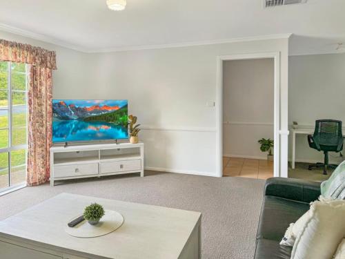 a living room with a couch and a flat screen tv at Suburban Bliss - Elegant Villa 1 in Wagga Wagga