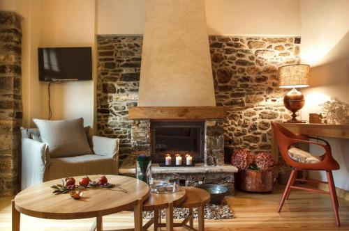 a living room with a stone fireplace and a table at Kalderimi Country House in Mouresi