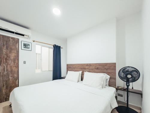 a bedroom with a white bed and a fan at Miraflores in Cali