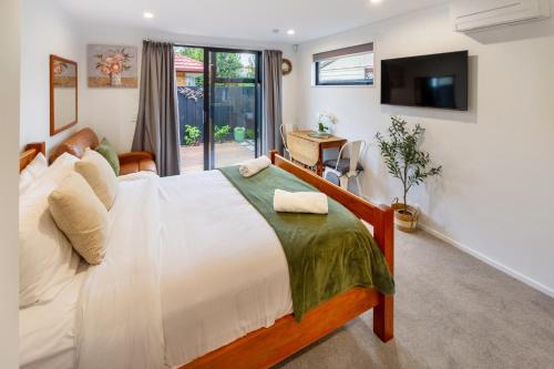 a bedroom with a large bed and a tv at The Nest - Modern Studio Retreat with Parking in Christchurch