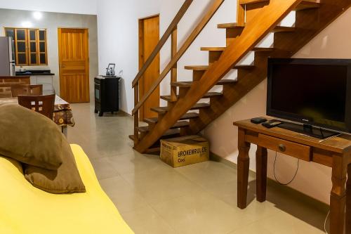 uma sala de estar com televisão e uma escadaria em Casa da família Castro em Capão da Canoa