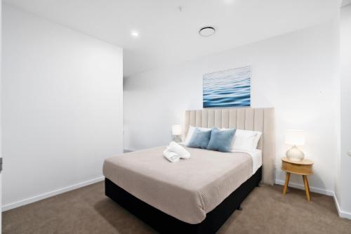 - une chambre blanche avec un lit et des oreillers bleus dans l'établissement New waterview two bedrooms, à Gold Coast