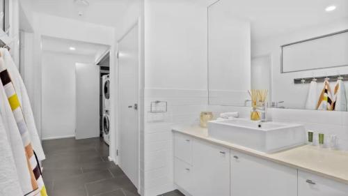 ein weißes Badezimmer mit Waschbecken und Spiegel in der Unterkunft Pacific Piers in Coffs Harbour