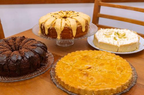 drie taarten op borden op tafel bij Pousada Portal da Serra in Campos do Jordão