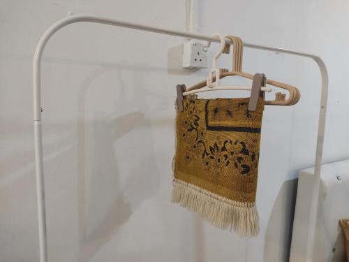 ein Teppich, der mit einem Besen an einem Gestell hängt in der Unterkunft Homestay RnR CafeStay in Kampong Pengkalan Maras