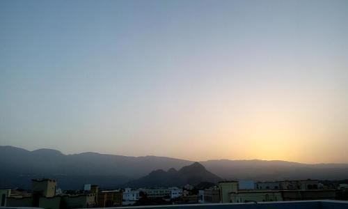 a sunset over a city with mountains in the background at Al Hamra Guest House in Al Ḩamrāʼ