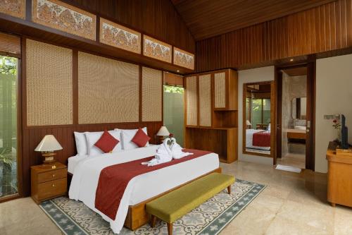 a bedroom with a large bed and a television at Nauma Ubud Villa in Ubud
