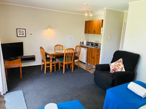 Una sala de estar con una mesa y una cocina. en Awatea Park Motel, en Palmerston North