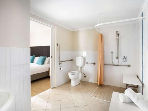 a bathroom with a toilet and a bed at Mantra Ettalong Beach in Ettalong Beach