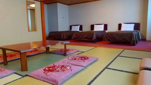 a room with a table and some chairs and mats at 佐久一萬里温泉ホテル in Saku