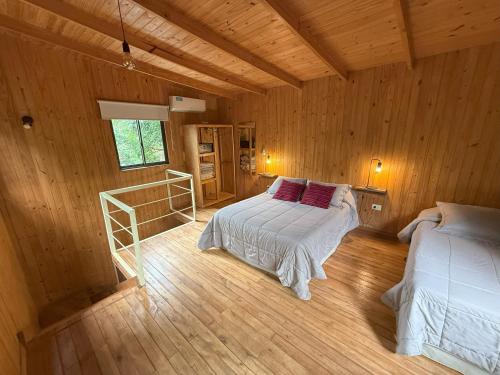 a bedroom with two beds in a wooden cabin at Cabaña Oma Iguazú in Puerto Iguazú