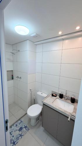 a white bathroom with a toilet and a sink at Mila rooftop apto 308 in Tamandaré
