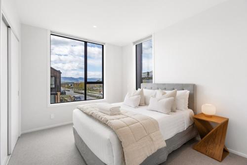 ein weißes Schlafzimmer mit einem Bett und einem großen Fenster in der Unterkunft Modern 3-Bed Villa with Mountain Views in Wanaka