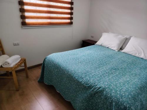 a bedroom with a bed with a blue blanket and a window at Kabañas Bosque De Alamos in Puerto Aisén