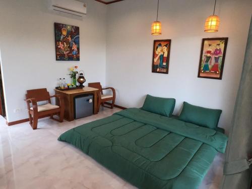 een slaapkamer met een groen bed en een tafel bij สมายด์ ฮ่อมนา เรสเฮาท์ Smile Homna Resthouse in Ban Mae Chong