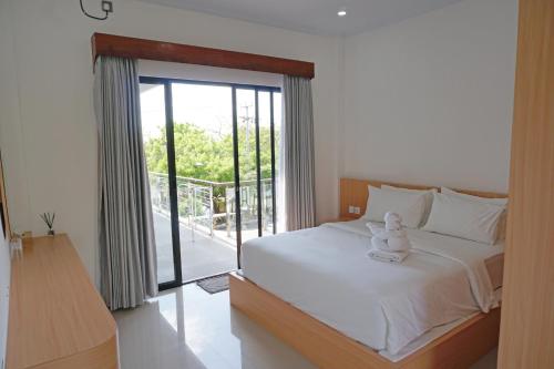 a bedroom with a white bed and a balcony at Habitat Boutique Dive Resort in Tulamben