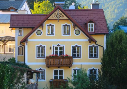 ein gelbes Haus mit einem Balkon mit Blumen darauf in der Unterkunft Villa Leni - Premium Apartments in Bad Ischl