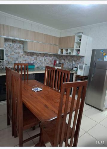 eine Küche mit Holztisch und Kühlschrank in der Unterkunft Casa linda in Ananindeua