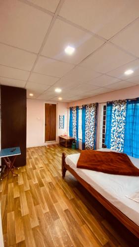 a bedroom with a large bed with blue curtains at Lijo Ruban Home Stay in Kodaikānāl