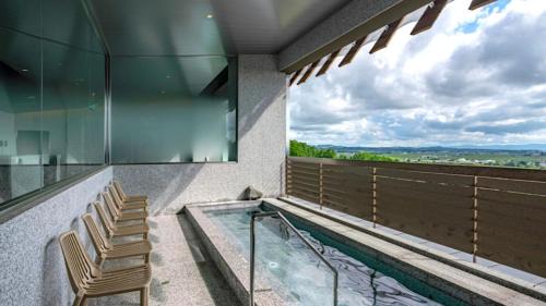a balcony with chairs and a hot tub with a view at The Peak Villa Suite Hokkaido in Higashikawa