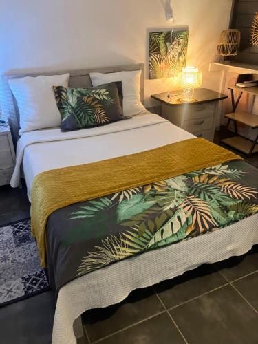 a bedroom with a large bed with a tropical bedspread at Tilys lodge in Capesterre-Belle-Eau