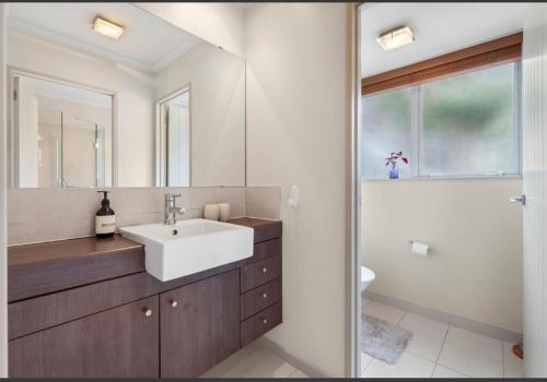 a bathroom with a sink and a mirror at Cozy Water-View 2-Bdrm Suite in North Shore in Auckland