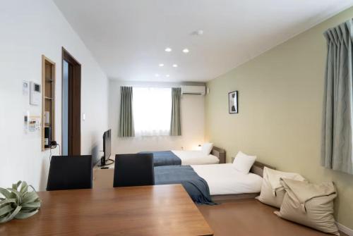 a hotel room with two beds and a table at The Peak Villa Suite Hokkaido in Higashikawa