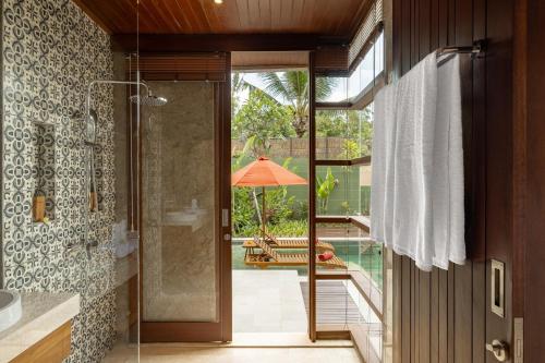 Baño con puerta de cristal que da a un patio en Nauma Ubud Villa, en Ubud