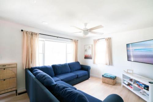 een woonkamer met een blauwe bank en een tv bij Beachside Bungalow - Charlestown RI in Charlestown