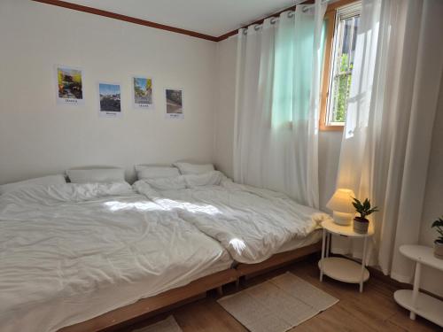a white bedroom with a bed and a window at 종로익선 스테이 in Seoul
