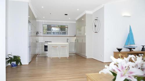 a kitchen with white walls and a hardwood floor at Summer Splendor - Ettalong Beach in Ettalong Beach