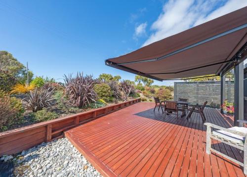 a deck with an umbrella and a table and chairs at Lighthouse-hideaway in Cape Foulwind