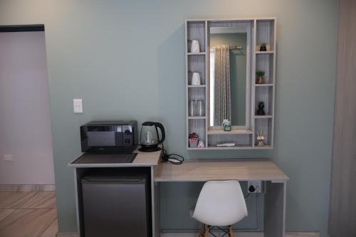 a desk with a microwave and a computer on it at GuestHouseVine&Stone in Clarens
