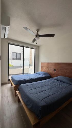 two beds in a bedroom with a ceiling fan at House Alto 58 Xochitepec Morelos in Xochitepec