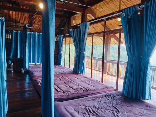 a room with two beds with blue drapes at Háng Đồng Ecolodge in Bắc Yên