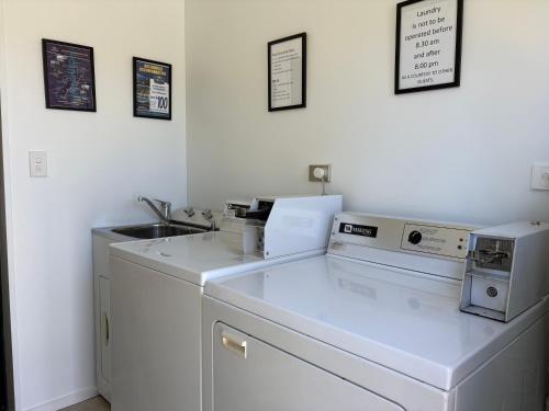 a white kitchen with a sink and a microwave at ASURE Central Gold Motel Cromwell in Cromwell