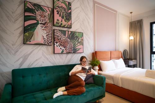 a woman sitting on a couch in a hotel room at Paxtonz Suites,1Utama,IKEA Damansara,SEGi,Desa Park in Petaling Jaya