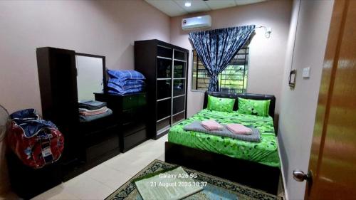 a bedroom with a green bed and a mirror at Homestay Kuala Berang Solehah Full Aircond Wifi & Netflix in Kuala Berang