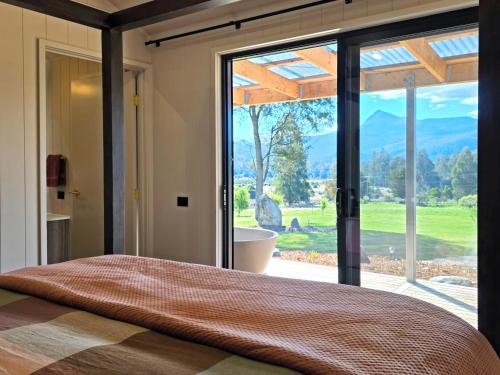 a bedroom with a large window with a view of a bathroom at Maydena Alpine Retreat in Maydena