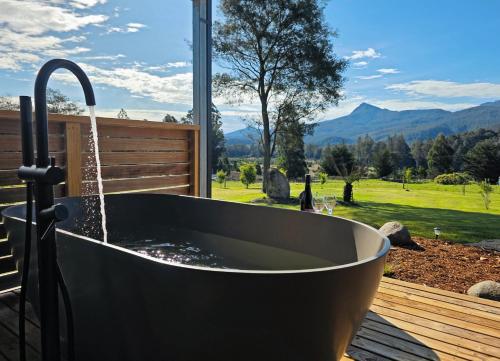 a bath tub on a deck with a view of the mountains at Maydena Alpine Retreat in Maydena