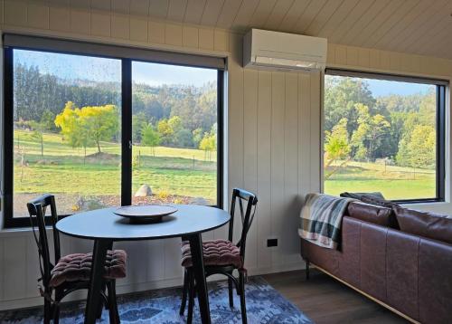 a table and chairs in a room with a couch at Maydena Alpine Retreat in Maydena