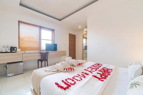 a bedroom with a white bed with red decorations on it at Srikrisna in Seminyak