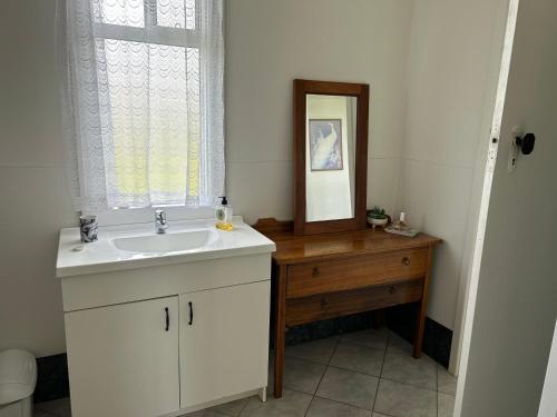 a bathroom with a sink and a mirror and a window at Grandad's farmhouse in Northcliffe