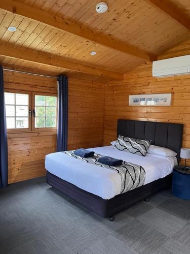 a bedroom with a large bed in a wooden room at Griffith Caravan Village in Yoogali