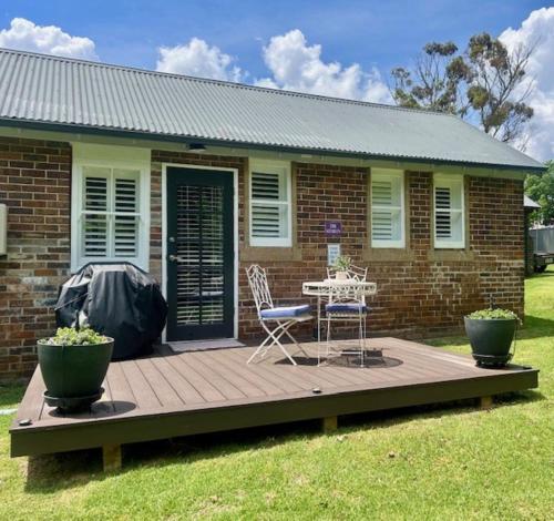 a deck with chairs and a table in front of a house at The Stables in Armidale