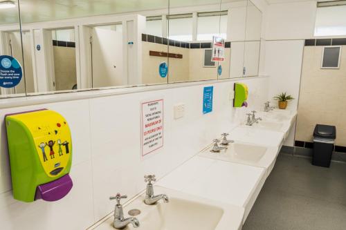 a public bathroom with three sinks and mirrors at BIG4 Perth Midland Tourist Park in Middle Swan