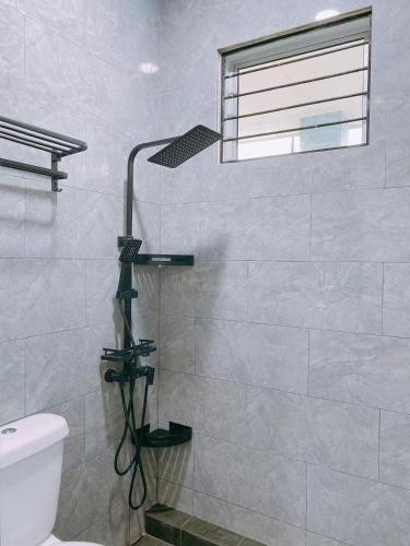 a shower in a bathroom with a toilet and a window at Homestay Sri Aman in Simanggang