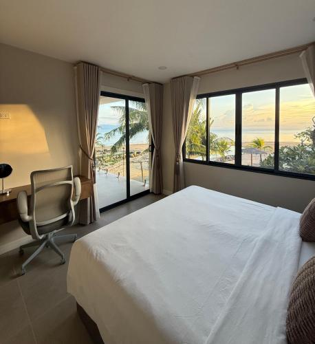 a bedroom with a bed and a desk and windows at Sabaii Bay Resort in Ban Tai